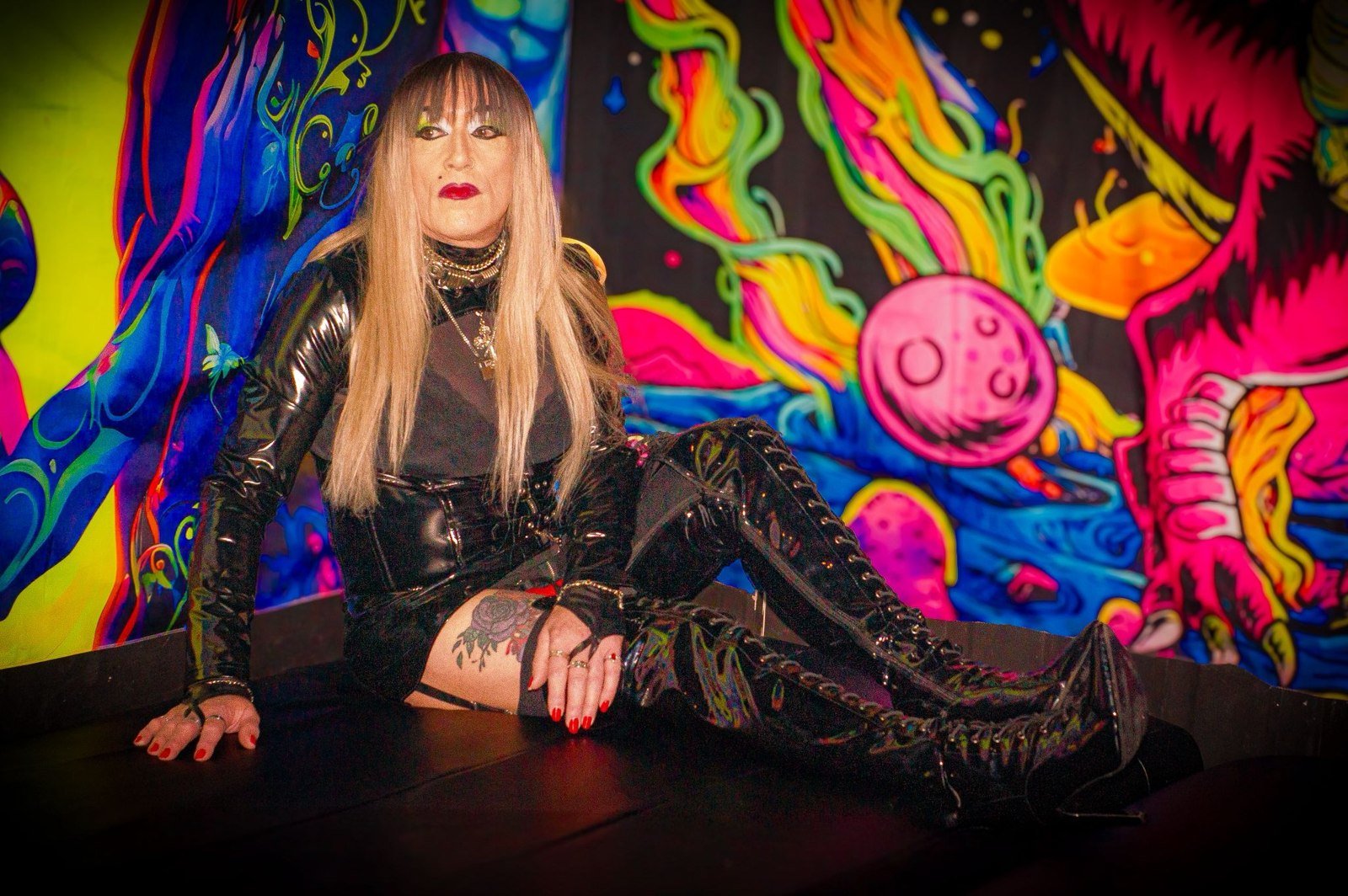 Alix, as identified by the supplied image filename, seated in front of colourful wall art.